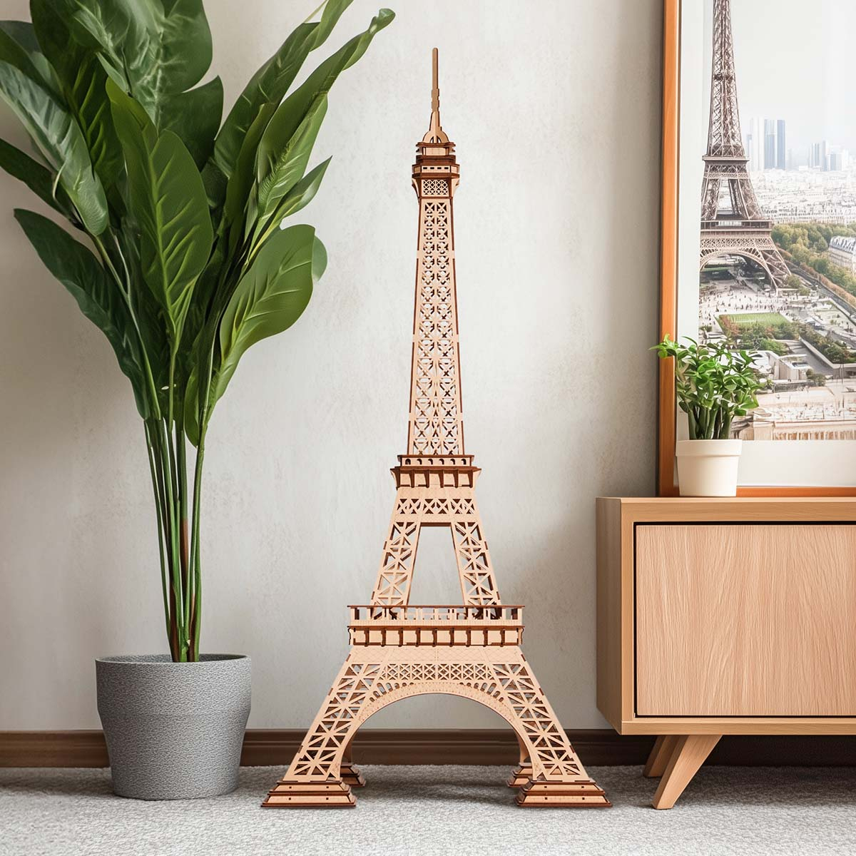 Un modello in legno della Torre Eiffel si trova accanto a una pianta in vaso e un armadio.
