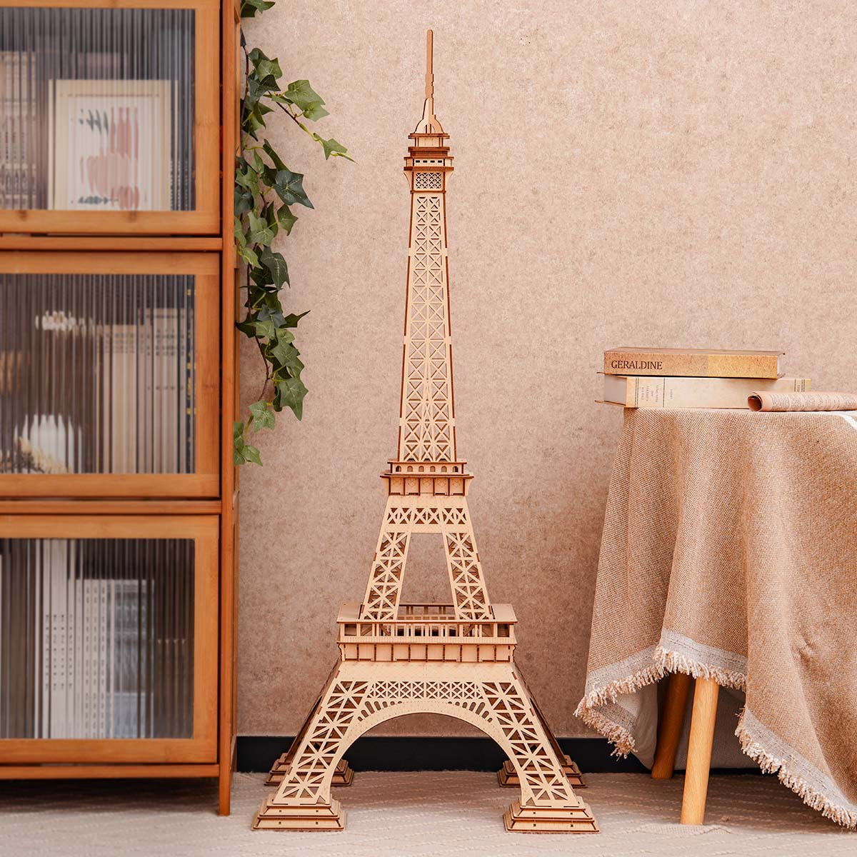 Un modello in legno della Torre Eiffel si trova accanto a un armadio e un tavolo con libri.
