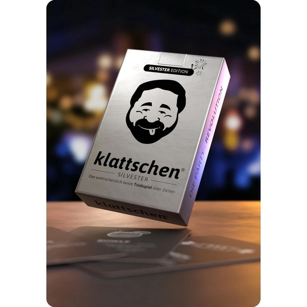 Una scatola di carte argentata con faccia ridente, "klattschen" e "Edizione Silvester".
