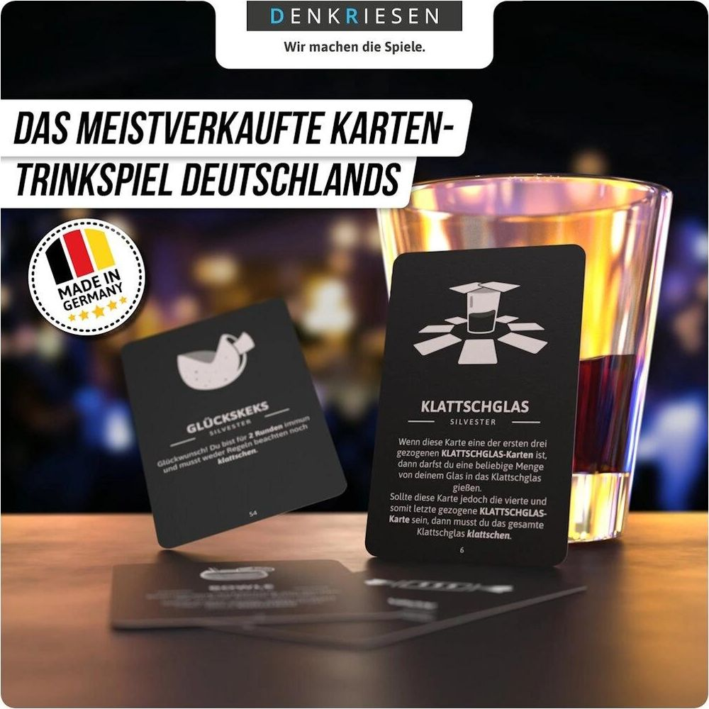 Carte da gioco nere e un bicchiere di bevanda scura su un tavolo di legno.