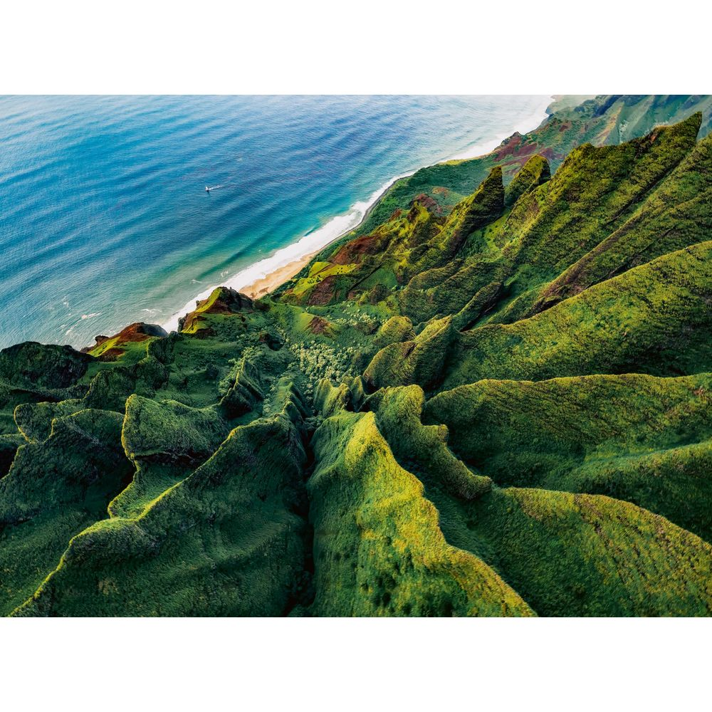 Grüne Berge fallen steil zum blauen Meer mit weißer Brandung ab.
