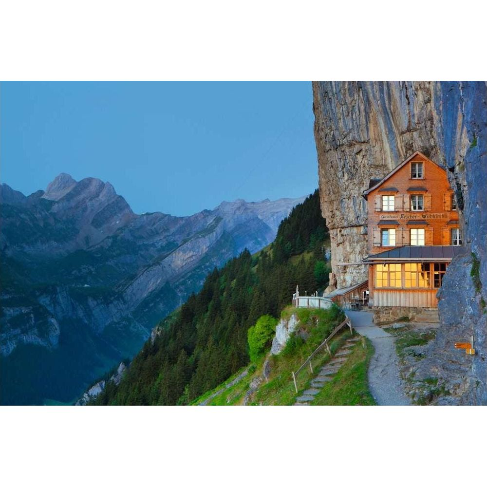 Une maison d'hôtes construite à flanc de falaise, avec des montagnes derrière.