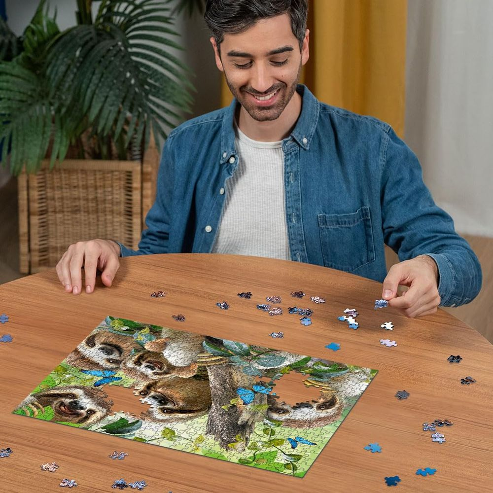 Mann vervollständigt Puzzle mit Faultieren und Schmetterlingen auf Holztisch.