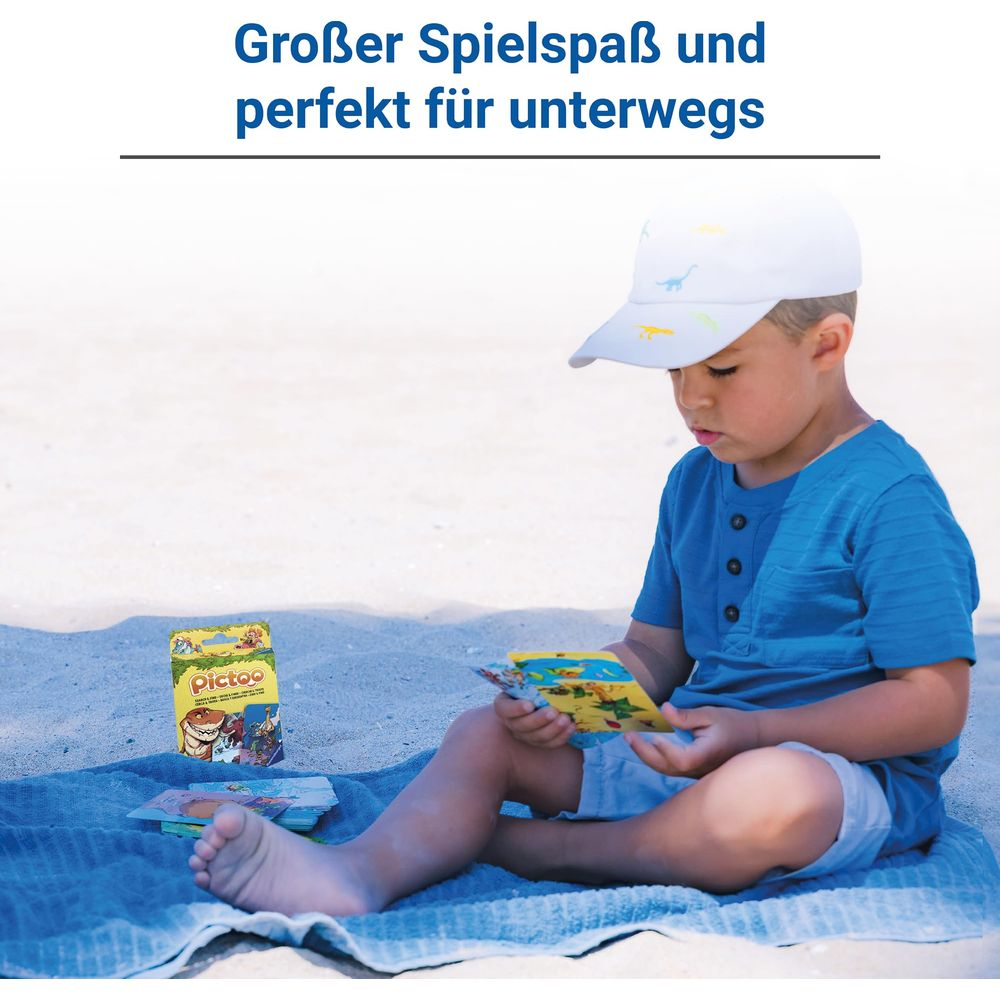 Ein Junge auf dem Strand sitzt auf einer Decke und spielt mit Karten.