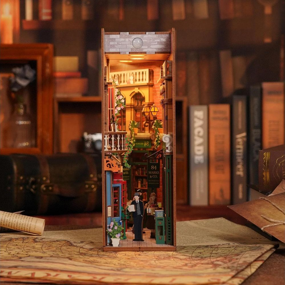Miniatur-Buchladen mit Figuren und Lichtern auf einem Kartentisch.