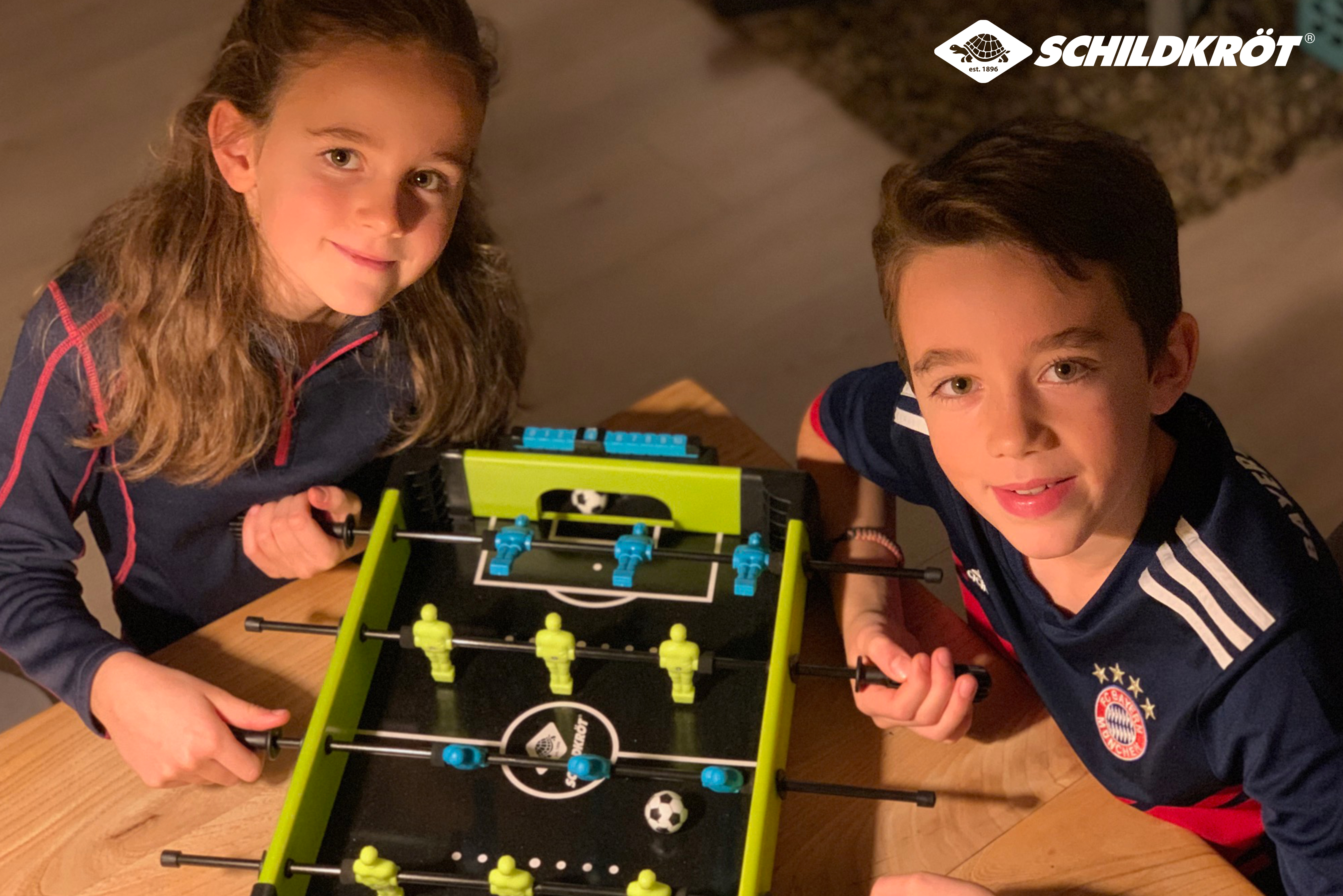Due bambini giocano a calcio balilla. Una bambina e un bambino giocano.