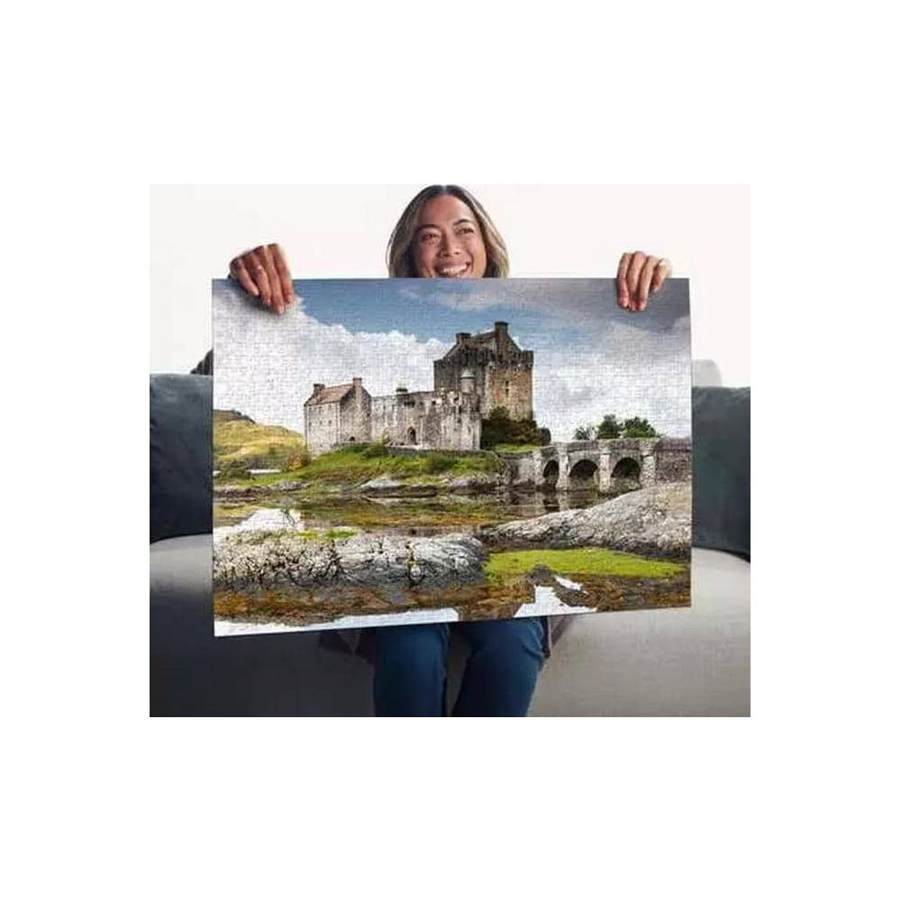 Femme tenant un puzzle de château avec pont sur l'eau.