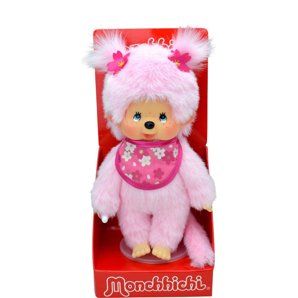 Ein rosa Monchhichi-Baby mit Blumen-Lätzchen und Blumen im Haar.