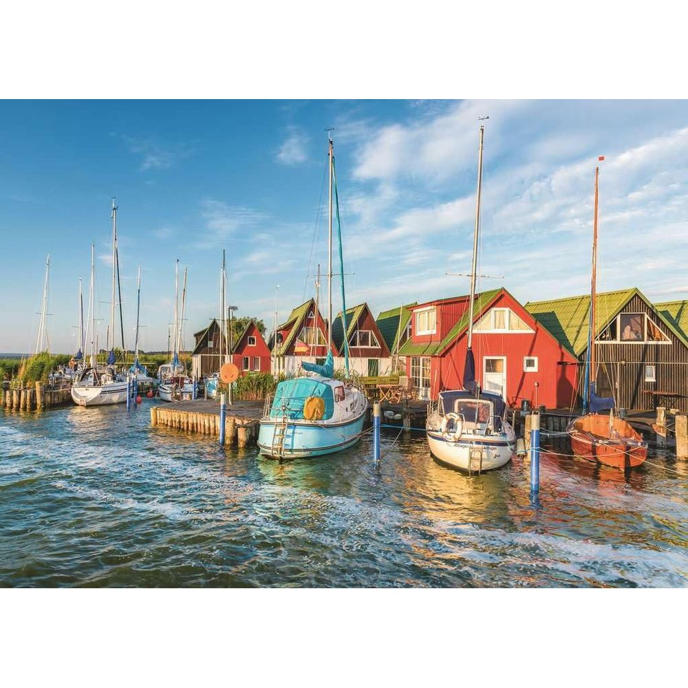 Bateaux amarrés dans un port avec des bâtiments rouges et des toits verts au bord de l'eau.