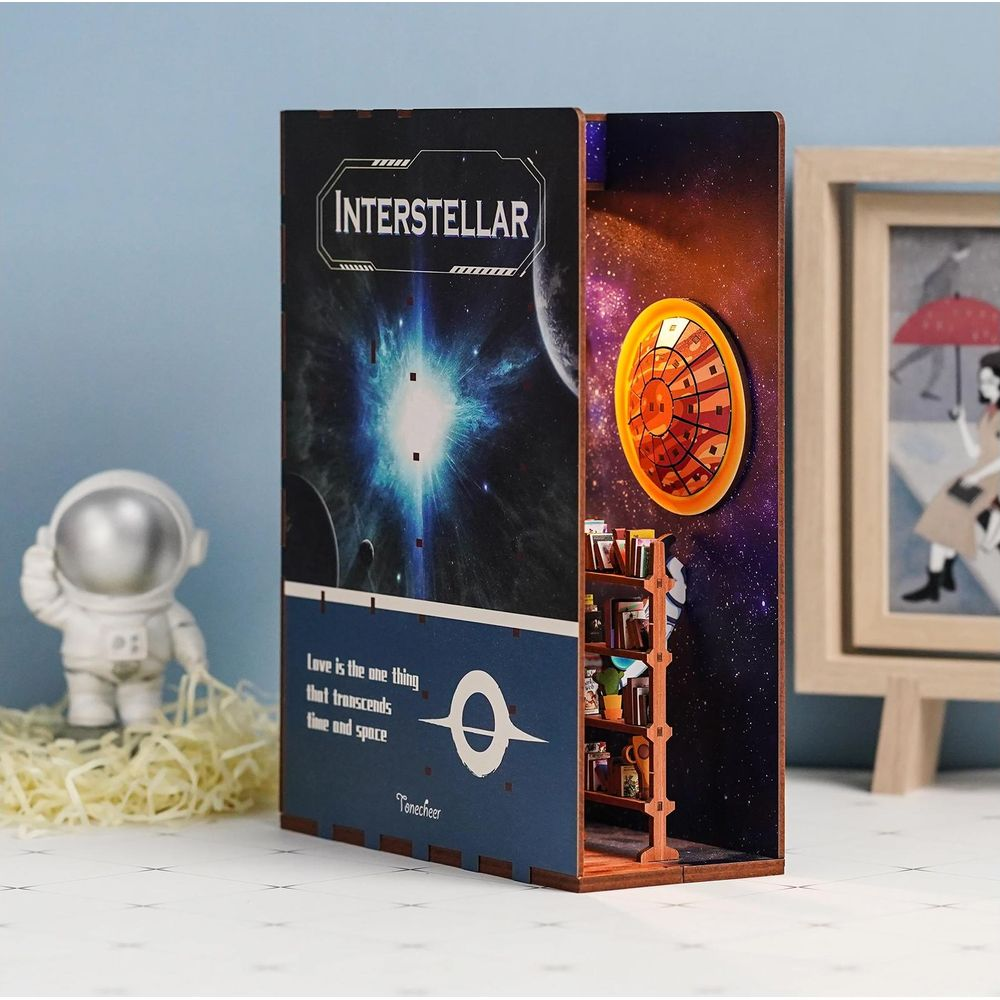 Modèle Interstellar avec astronaute, vaisseau et étoiles. Étagère à livres à l'intérieur.