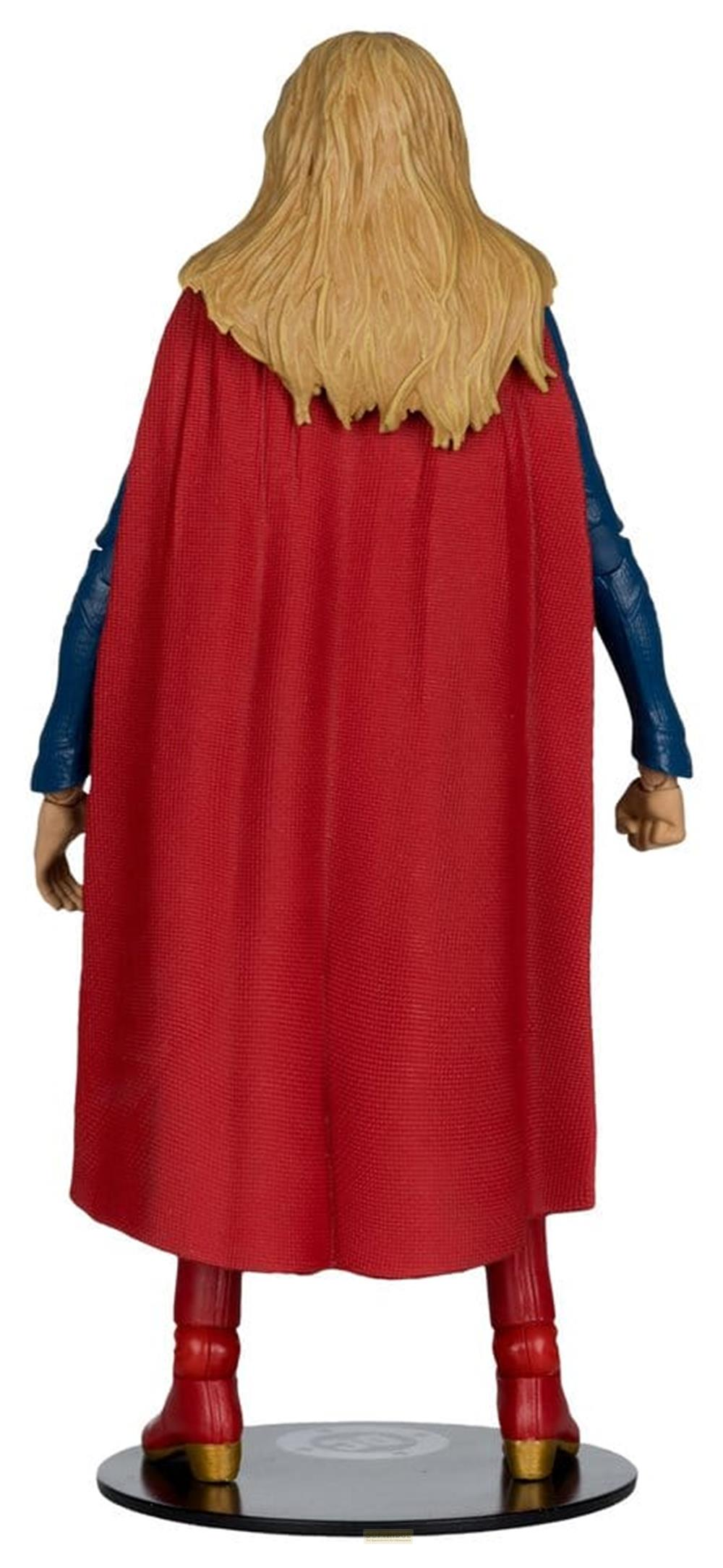 Figur von hinten: blonde Haare, roter Umhang, blaue Ärmel, rote Stiefel auf Podest.