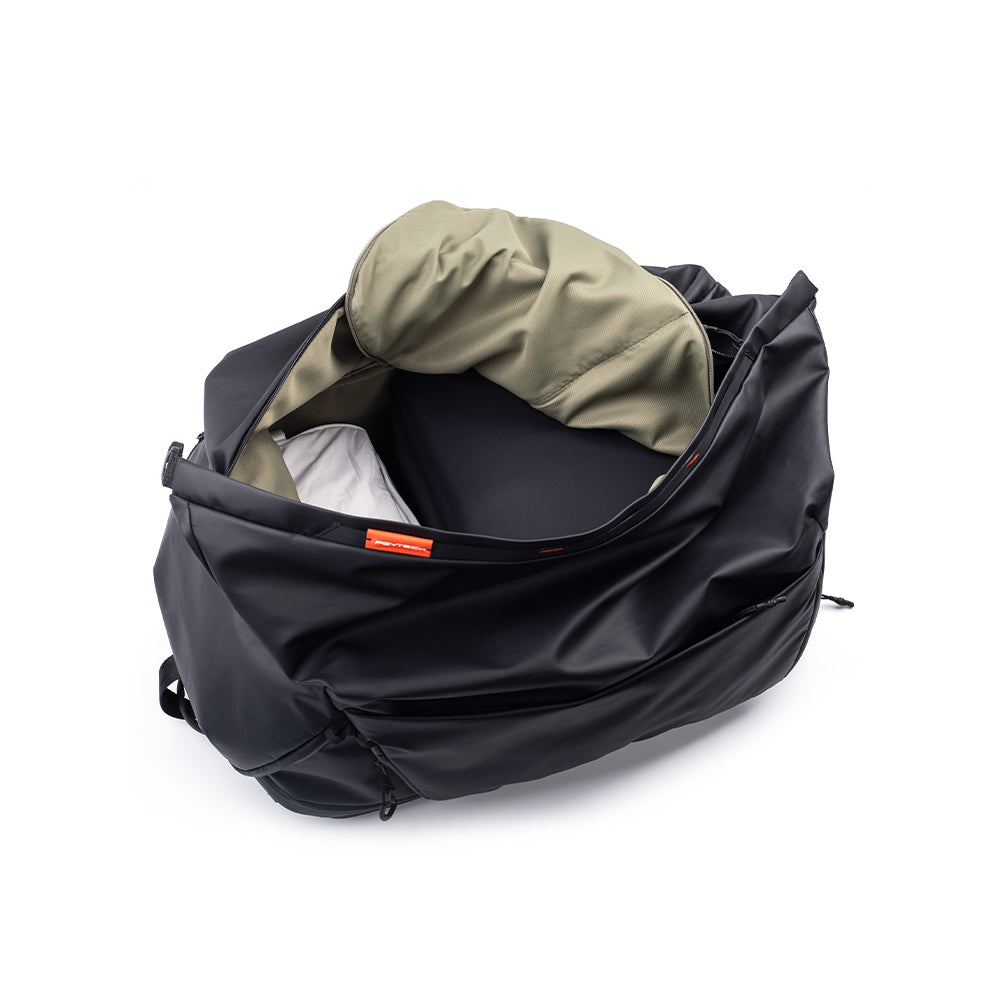 Ein offener schwarzer Rucksack mit khaki-farbenem Innenfutter und grauen Gegenständen.