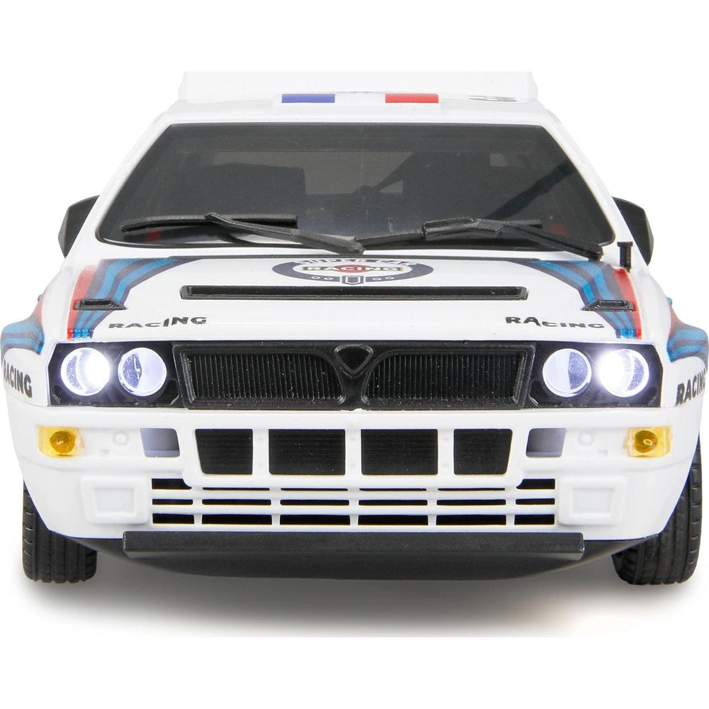 Vista frontal de un coche de carreras Lancia Delta blanco con rayas azules y rojas.