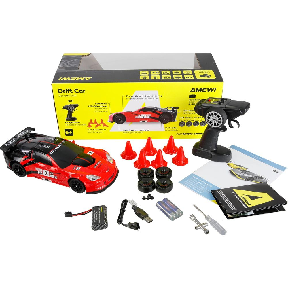 Un coche de deriva rojo a control remoto con accesorios como mando, baterías y conos.