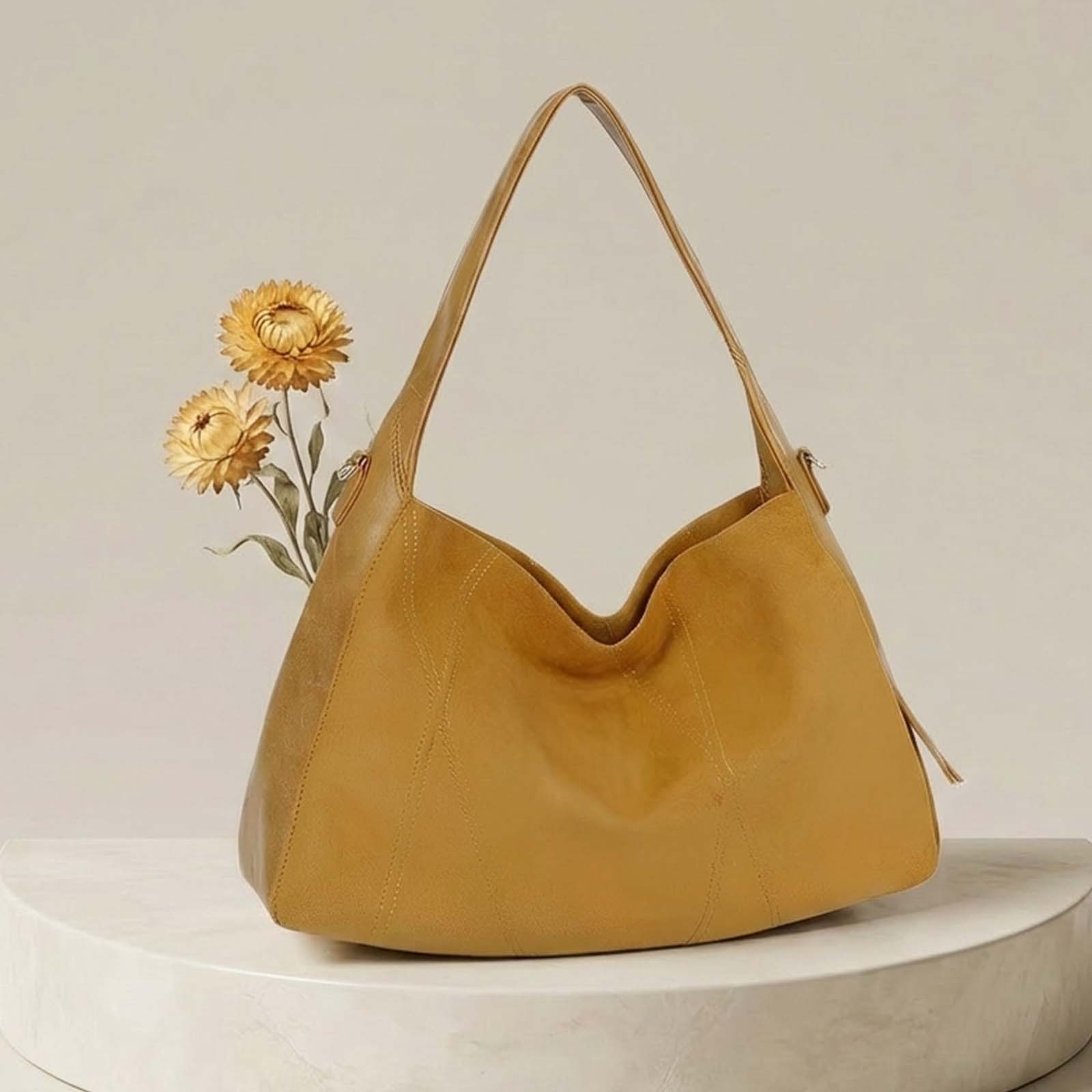 Un bolso de cuero amarillo mostaza con flores en un pedestal blanco.