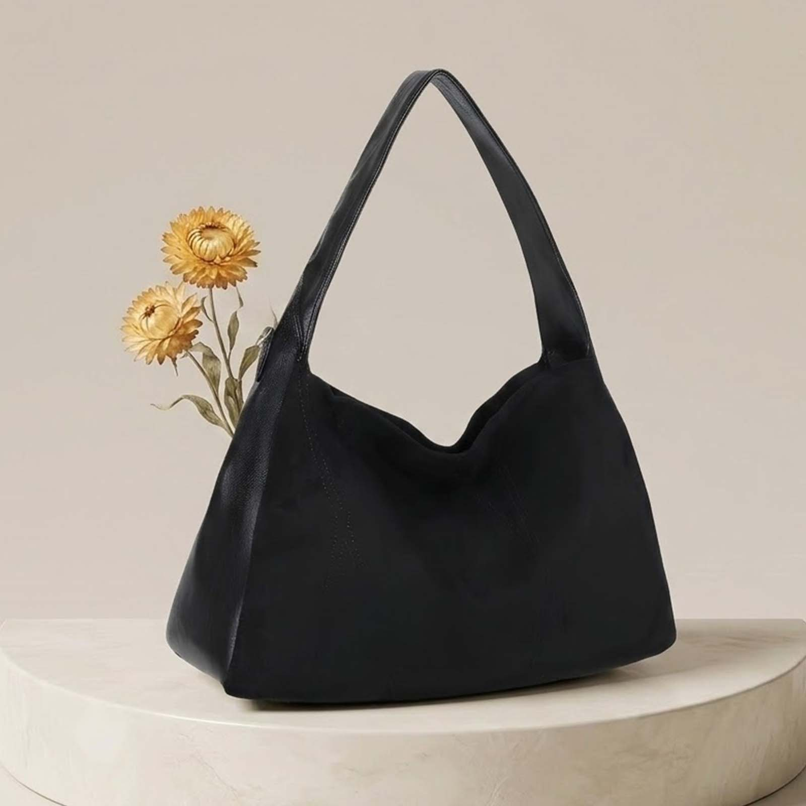 Bolso negro con dos flores secas amarillas sobre un pedestal redondo.