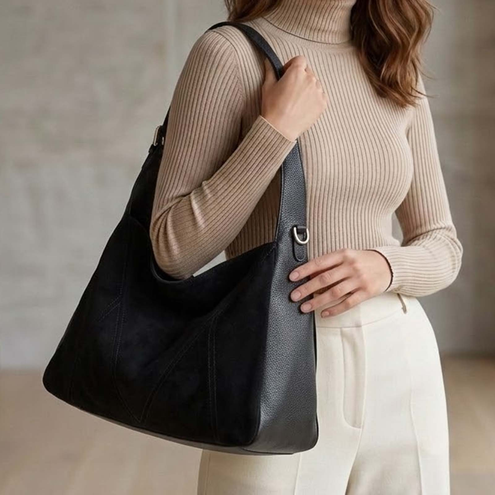 Una mujer lleva un jersey de cuello alto beige y pantalones blancos con un bolso negro.