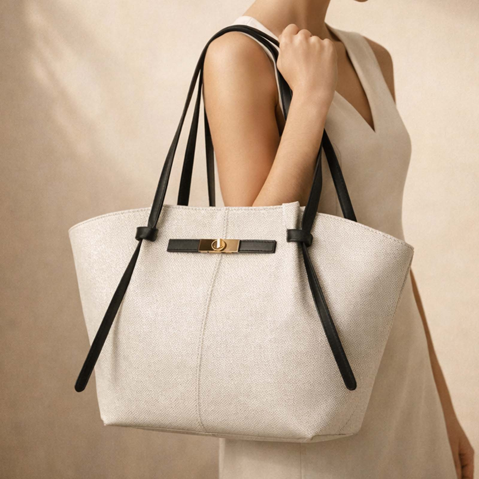 Una mujer lleva un bolso beige claro con correas negras y hebilla dorada.