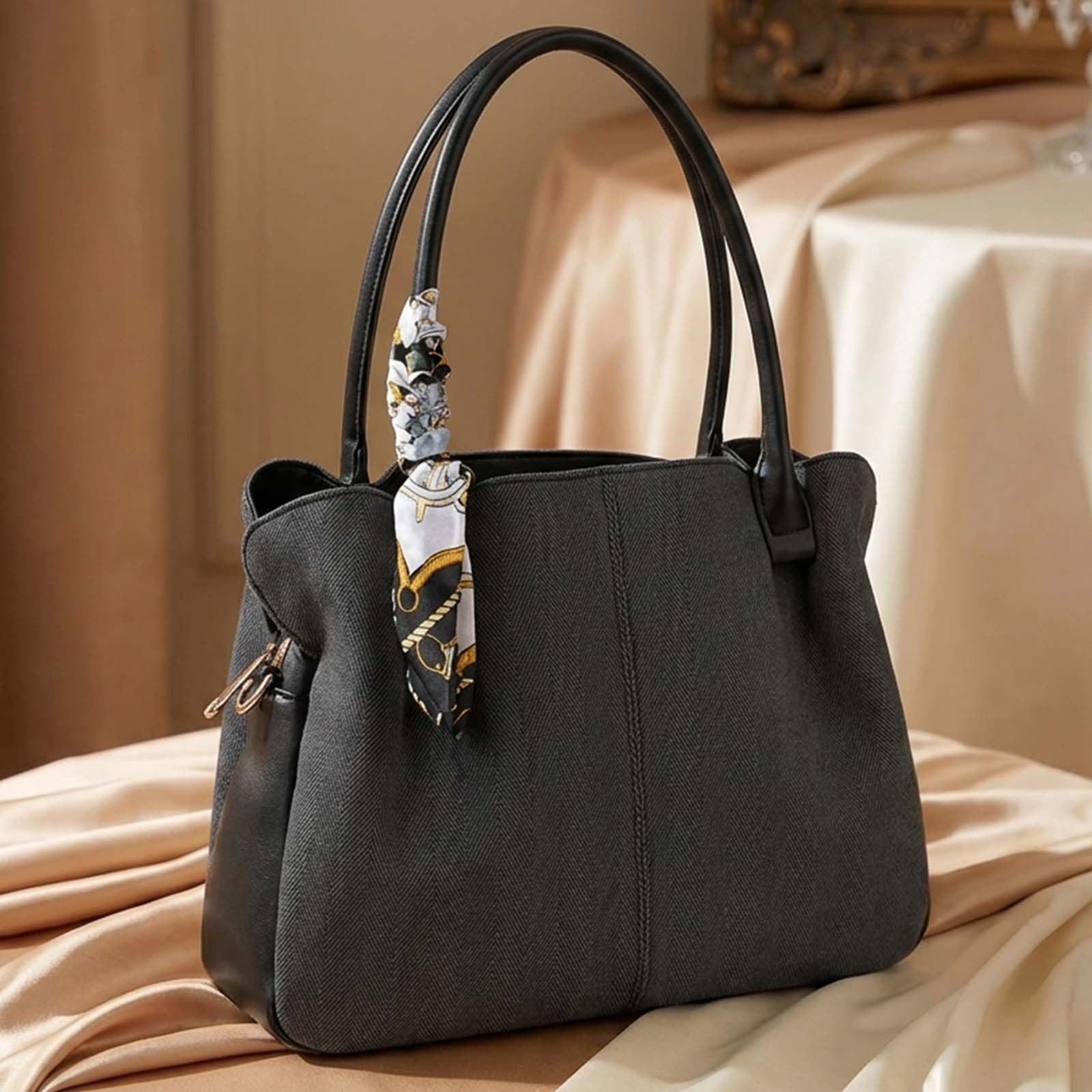 Un bolso tote oscuro con un pañuelo estampado atado a un asa.