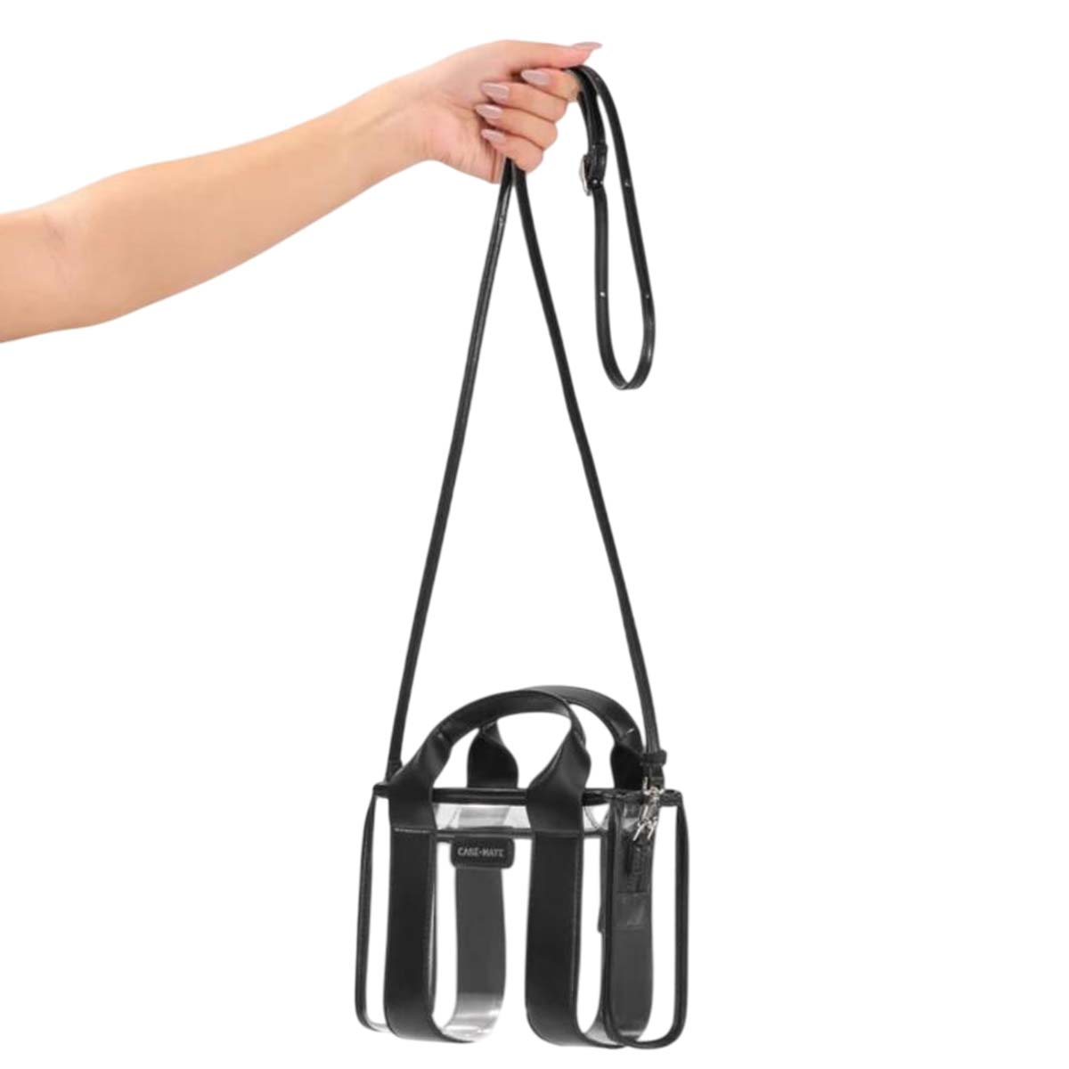 Una mano tiene una borsa tote trasparente con accenti in pelle nera.