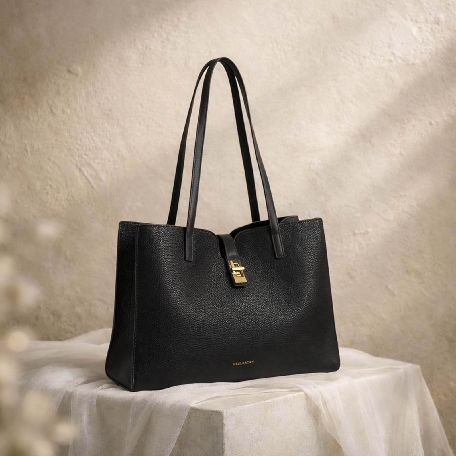 Un bolso tote negro de cuero texturizado con herrajes dorados.