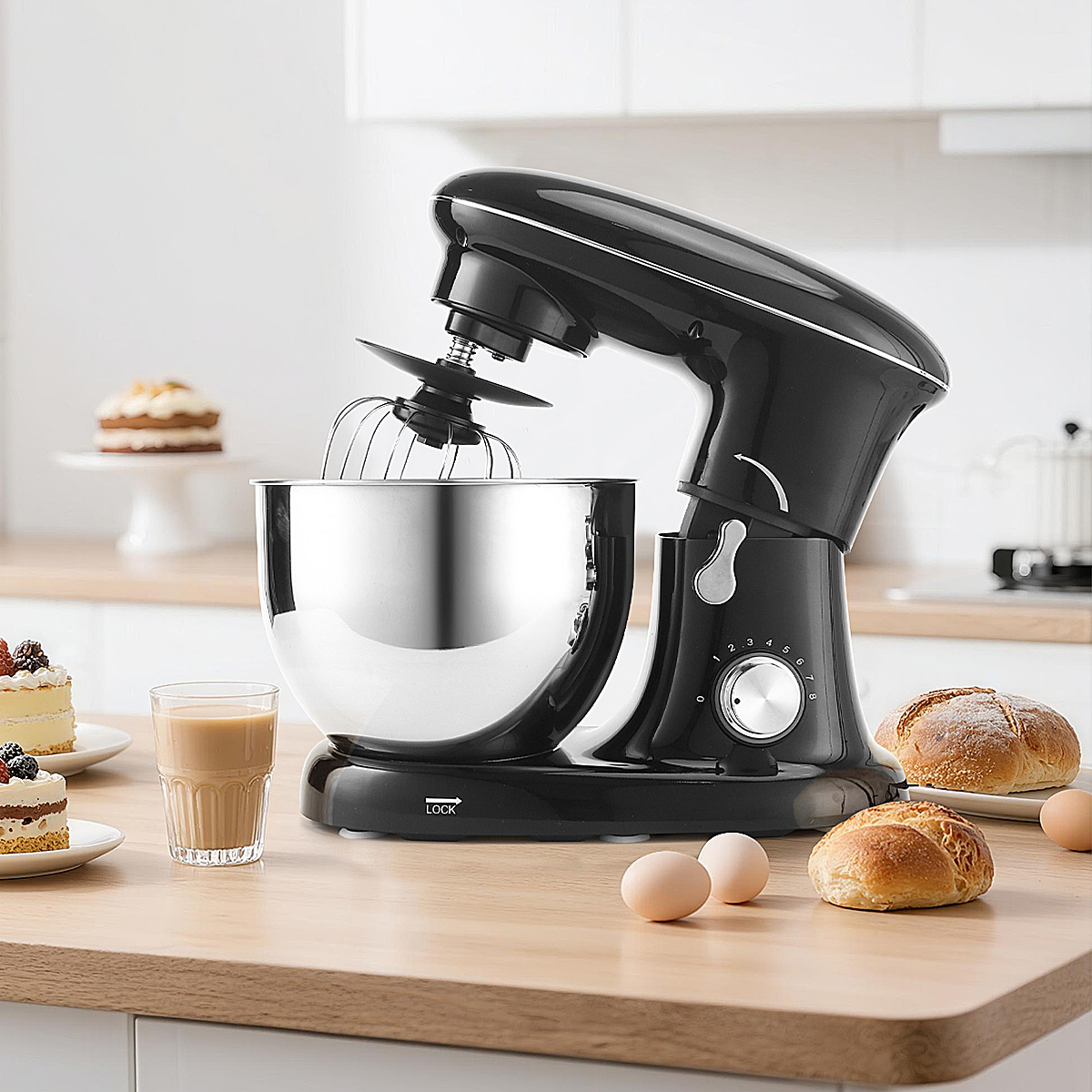 Ein schwarzer Standmixer mit Edelstahlschüssel, daneben Kuchen, Brot und Eier.