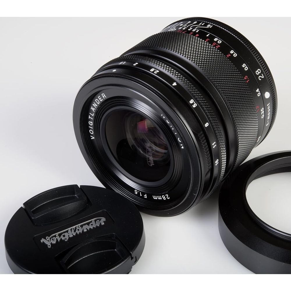 A black Voigtländer 28mm F1.5 lens with accessories on a white background.