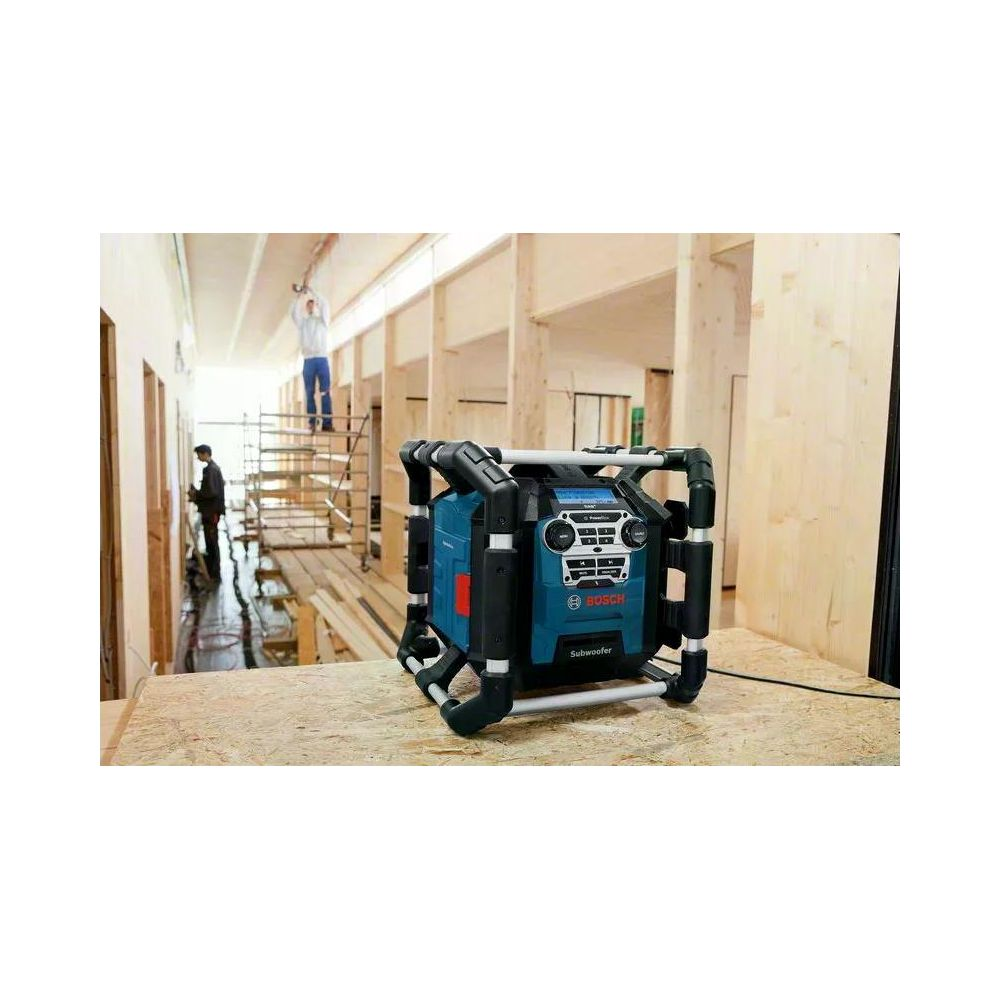 Subwoofer Bosch bleu avec cadre en acier sur chantier. Ouvriers sur échelle au fond.