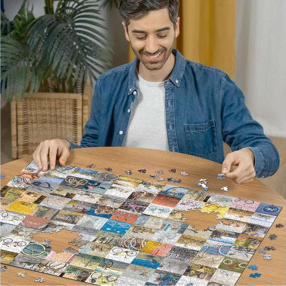 Homme place une pièce de puzzle avec des vélos. Table en bois, fond avec plante.