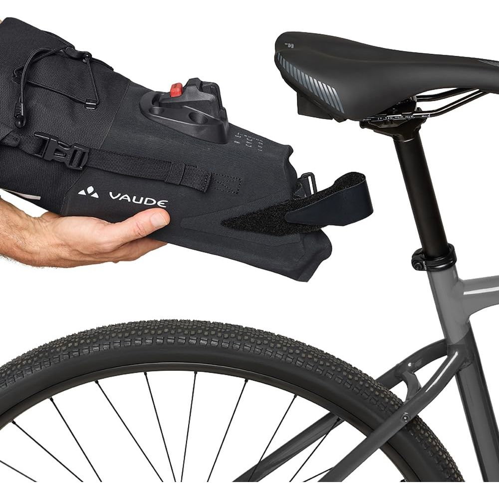 Un homme attache un sac de vélo noir VAUDE à une tige de selle.
