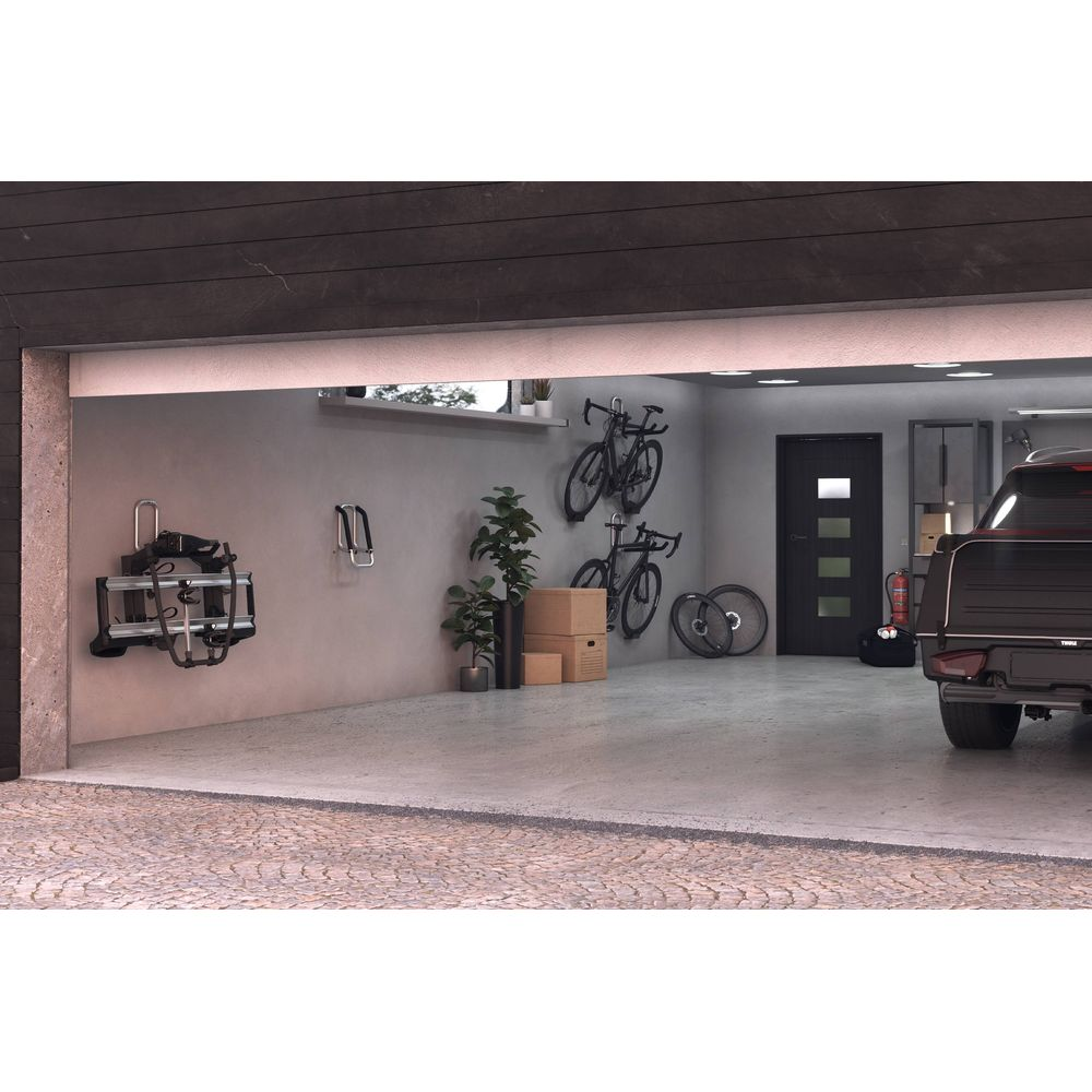 Eine Garage mit Fahrrädern an der Wand, einem Auto und einem Fahrradträger.