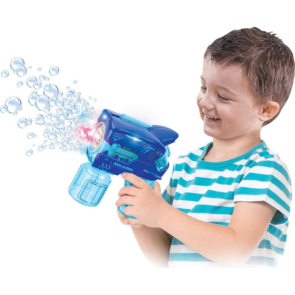 Un bambino tiene in mano una pistola sparabolle blu a forma di squalo.