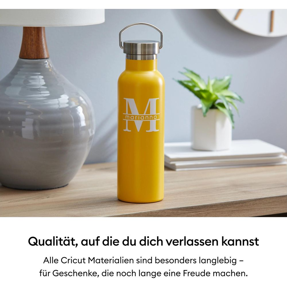 Ein gelber Becher mit Monogramm steht auf einem Nachttisch neben einer Vase.