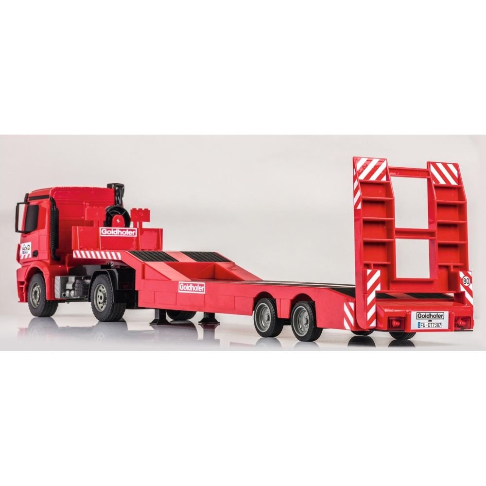 Roter Goldhofer Tieflader-LKW mit silbernen Rädern auf weißem Grund.