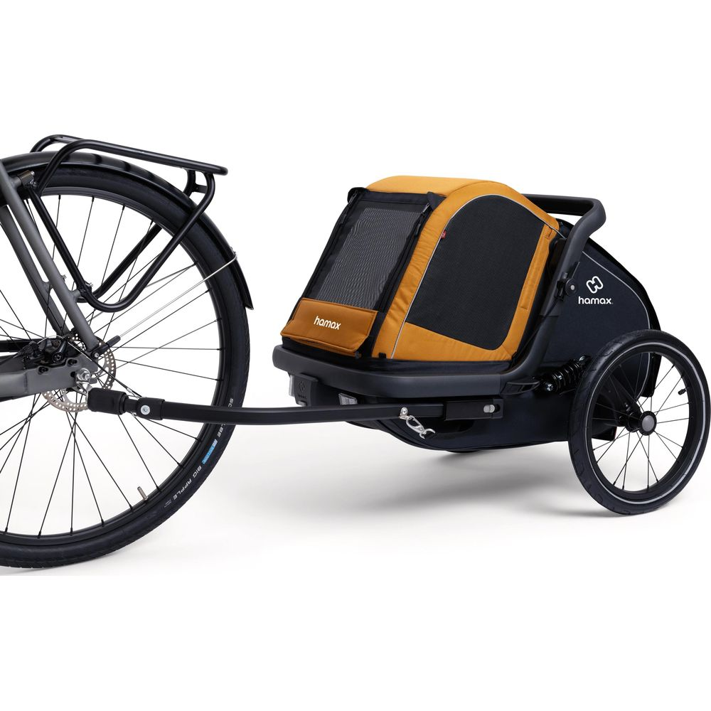 Ein Fahrrad ist an einem Kinderanhänger befestigt. Der Anhänger hat einen schwarzen Korpus und ein gelbes Verdeck.