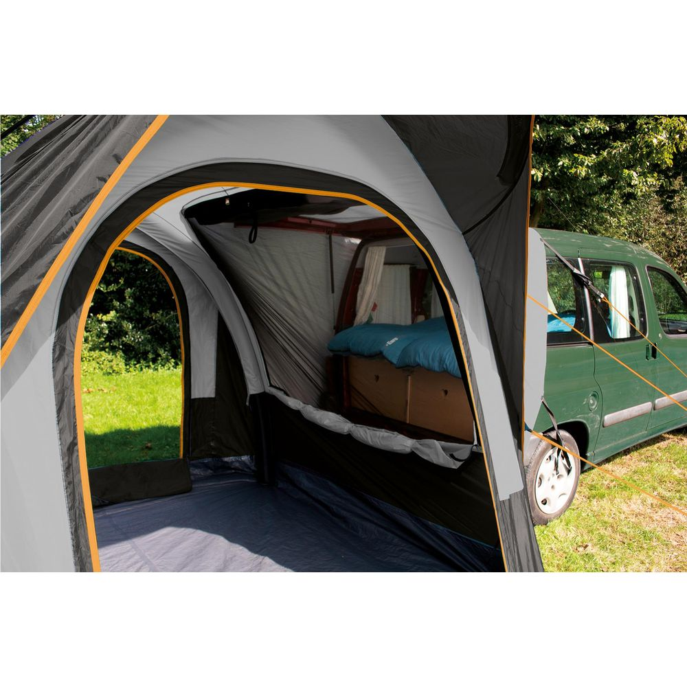 Innenansicht eines Zelts, das an einen grünen Van angeschlossen ist, mit einem Bett im Van.