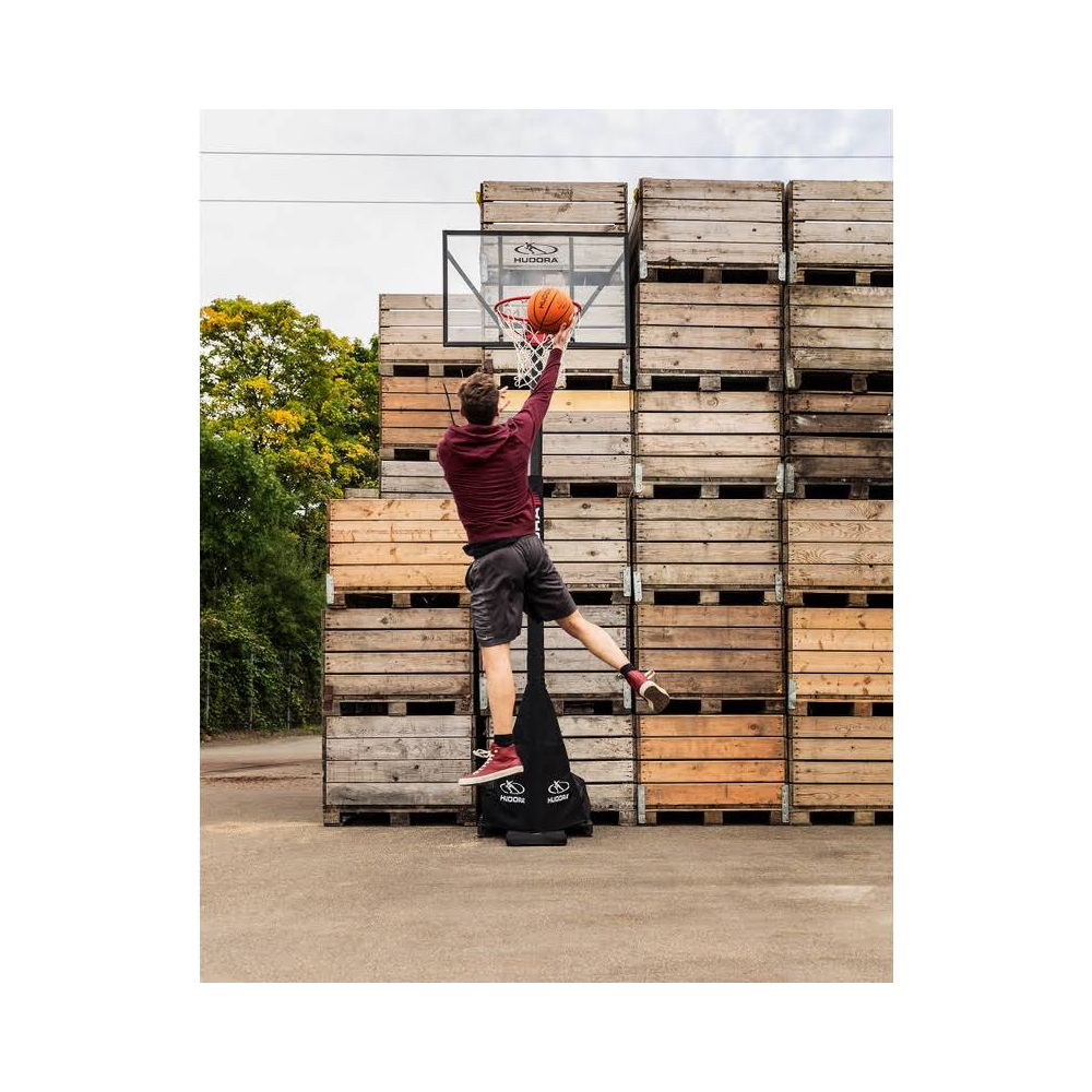 Uomo in maglia bordeaux schiaccia un pallone da basket.