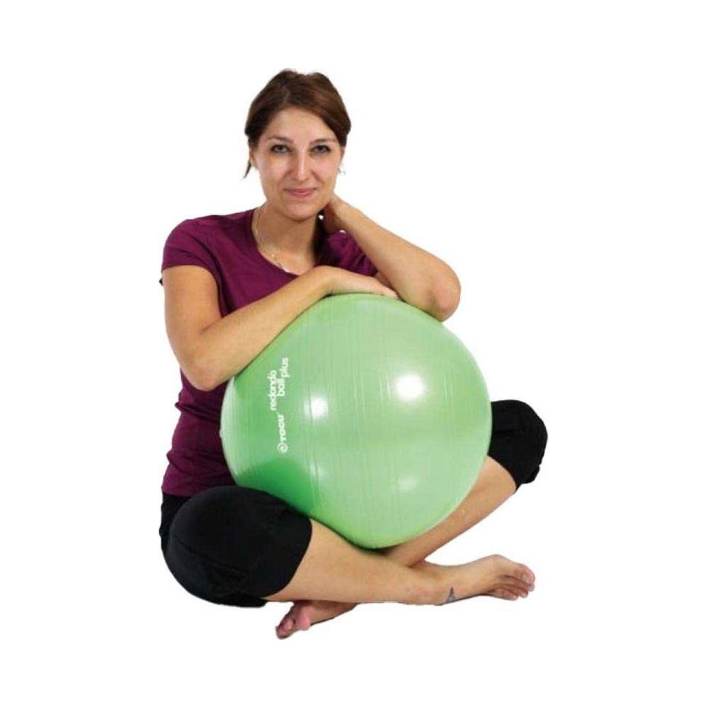 Eine Frau in lila Hemd und schwarzer Hose sitzt im Schneidersitz und hält einen hellgrünen Gymnastikball.