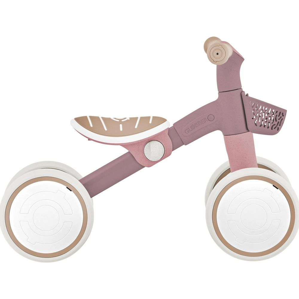 Una bici senza pedali rosa con quattro ruote, cestino e sedile regolabile.