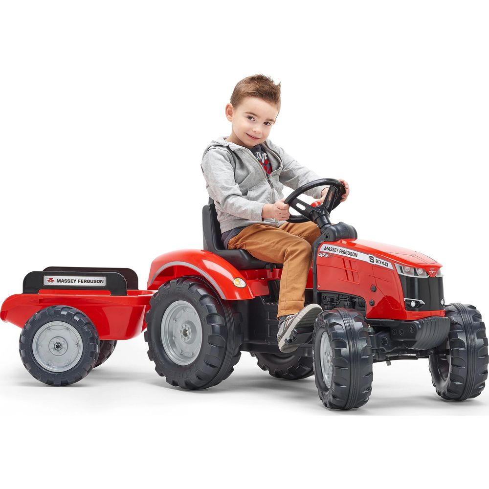 Ein Junge fährt einen roten Spielzeugtraktor mit Anhänger.