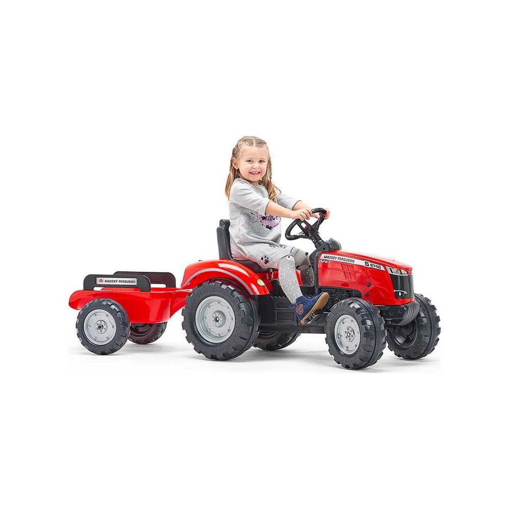 Ein kleines Mädchen fährt einen roten Spielzeugtraktor mit Anhänger.