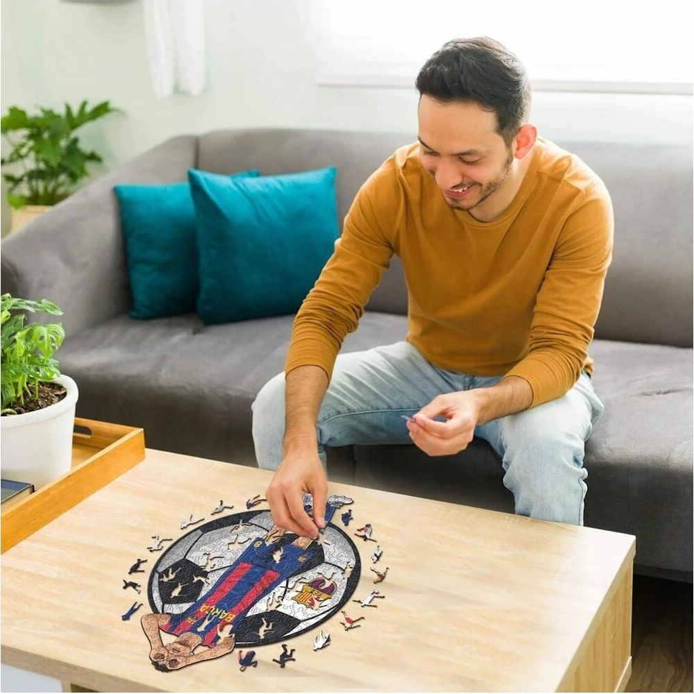 Mann setzt Puzzleteile zu einem Fußballer auf einem Tisch zusammen.