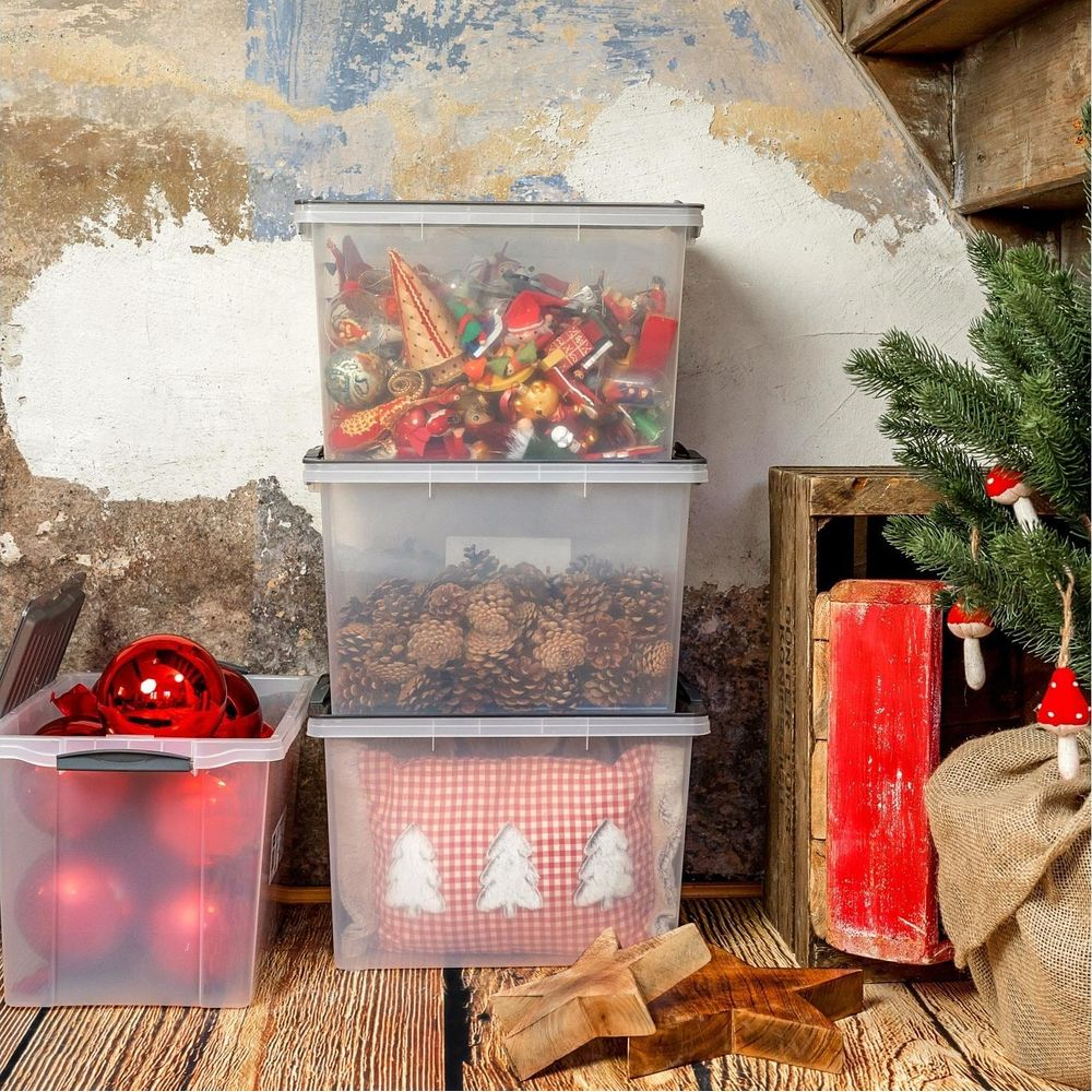 Weihnachtsdekoration in durchsichtigen Kisten gestapelt, mit Kiefernzapfen und Kugeln.