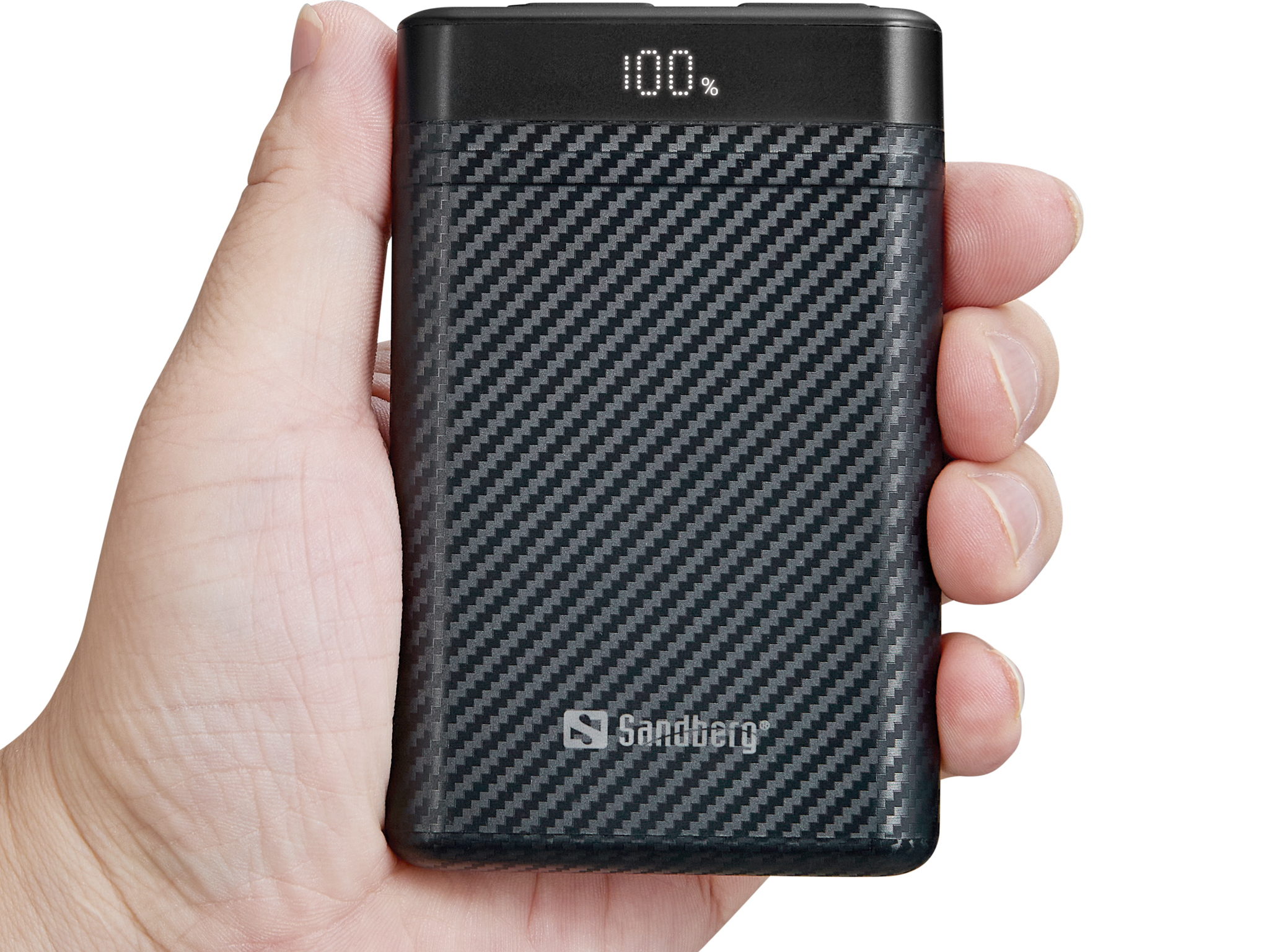 Una mano tiene un power bank Sandberg nero con motivo carbonio, carico al 100%.