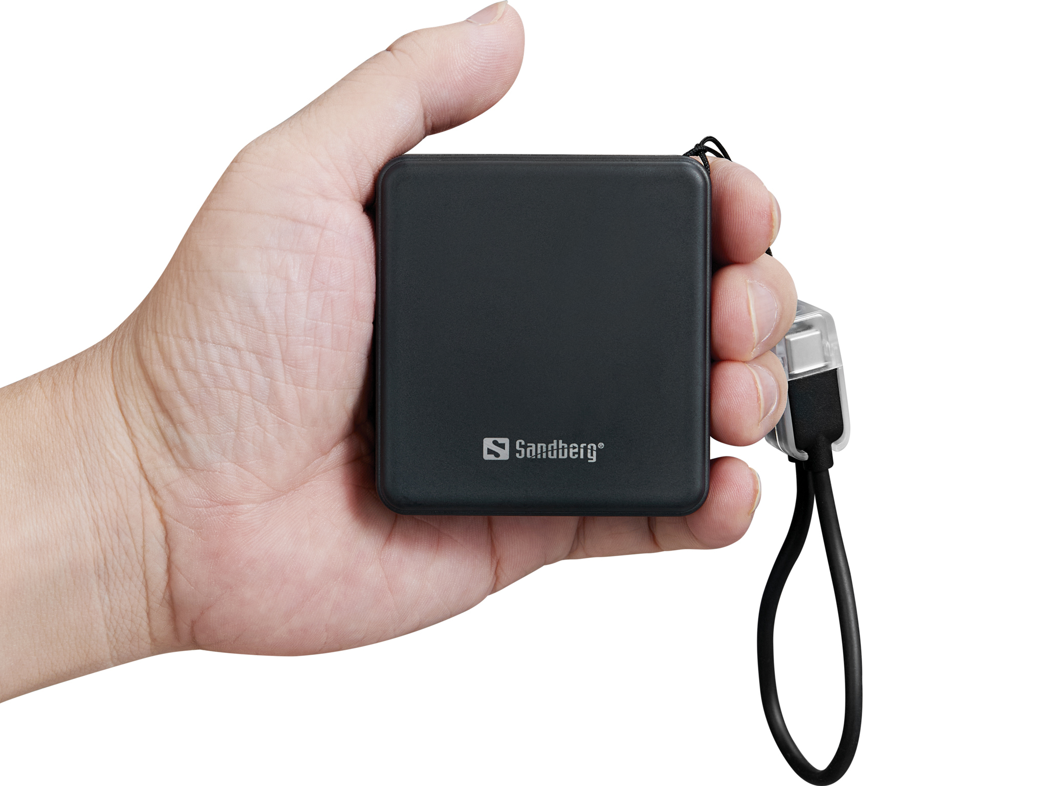 Une main tient un petit appareil Sandberg noir avec une lanière attachée.