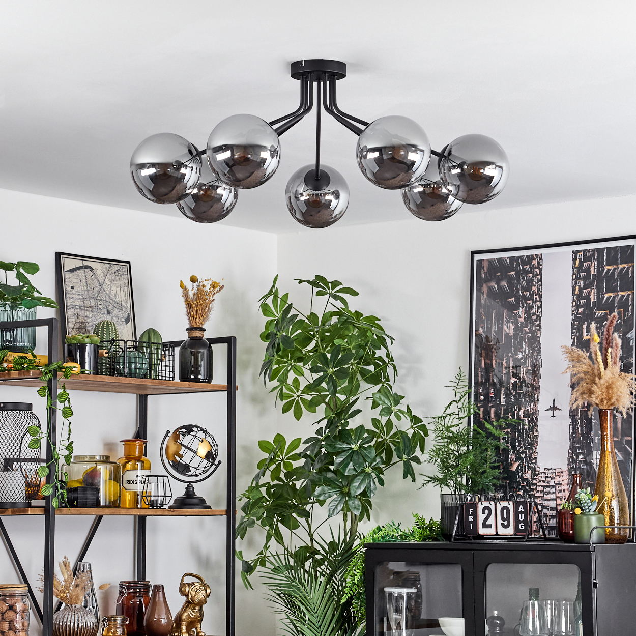 Ein moderner Deckenventilator mit sieben kugelförmigen, verspiegelten Lampenschirmen über einem Regal.
