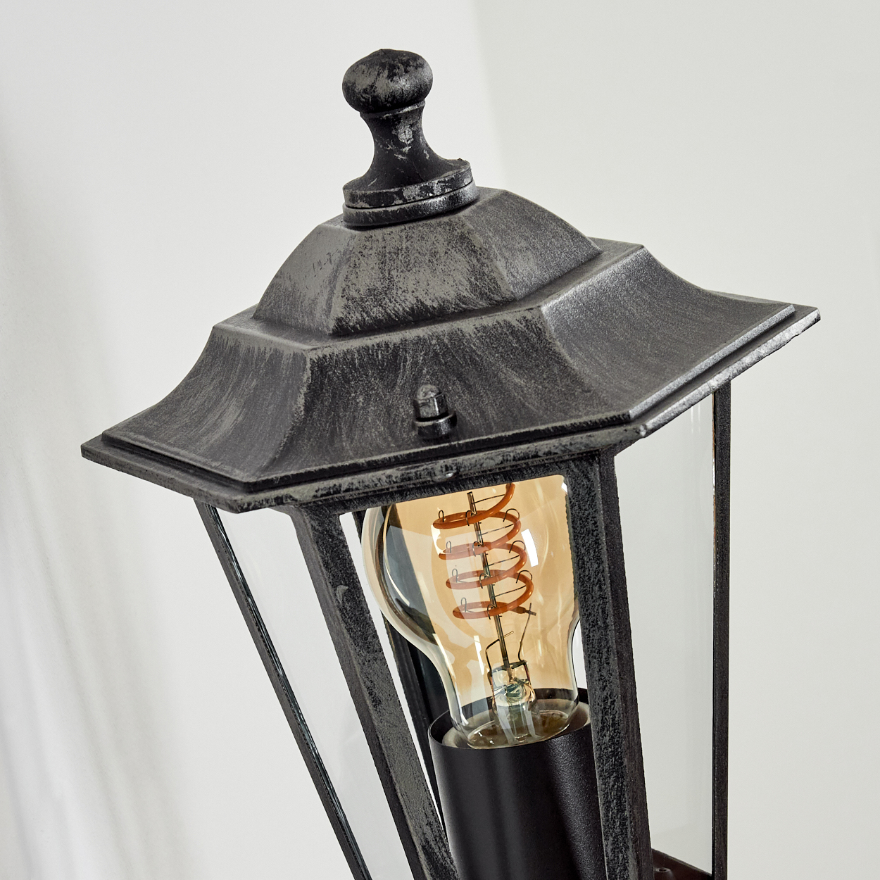 Eine antike Lampe mit schwarzem Metallrahmen, Glas und Glühbirne.