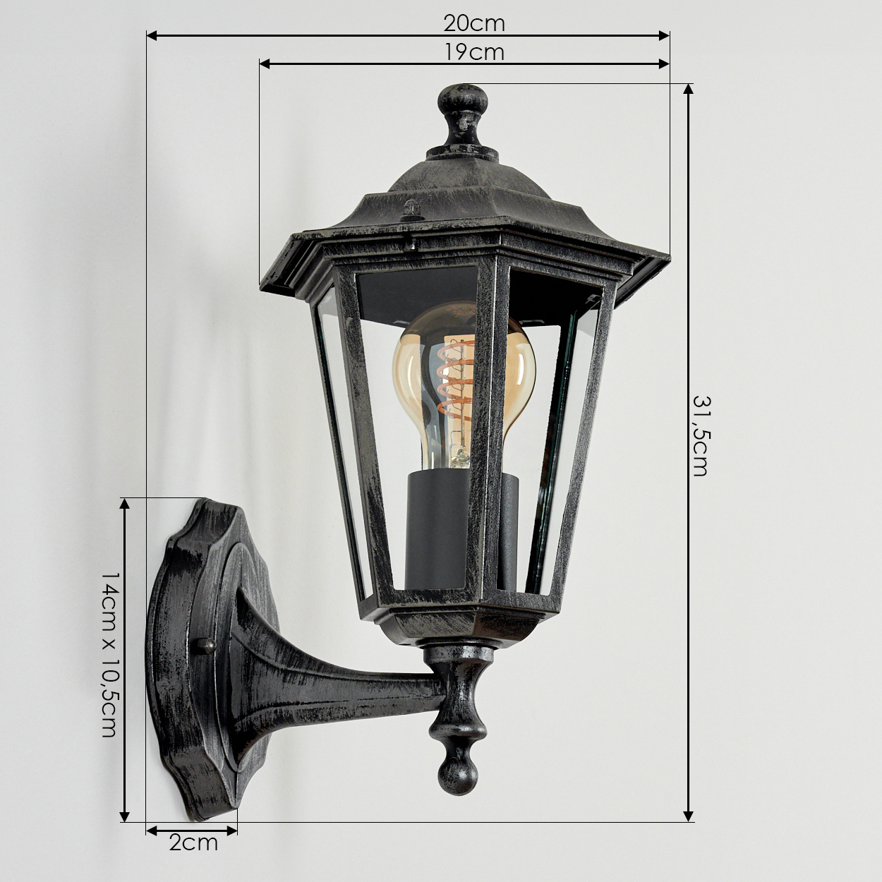 Eine dunkle Wandlaterne mit Glas paneelen und einem sichtbaren Leuchtmittel.