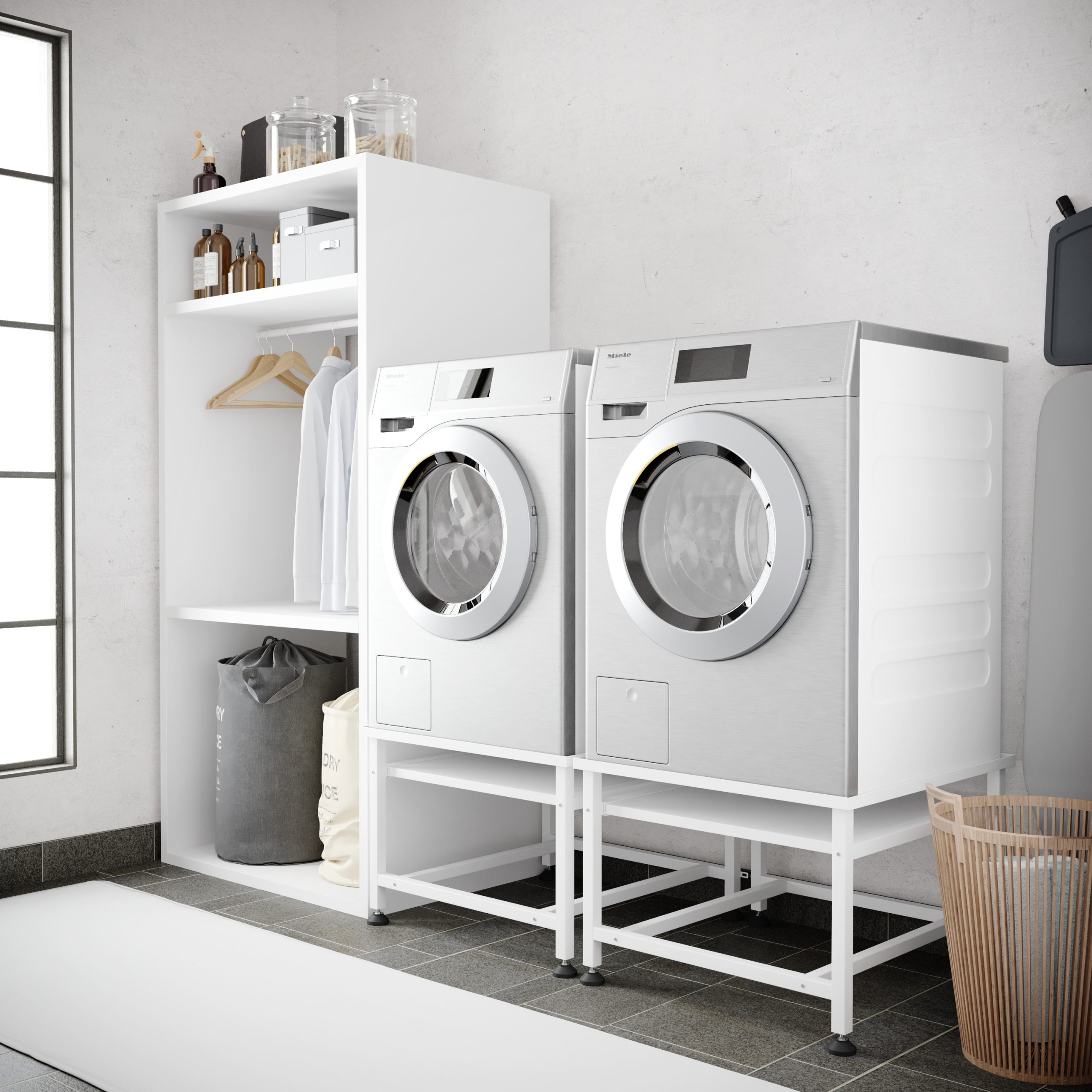 Two white Miele washing machines stand side-by-side on white pedestals.