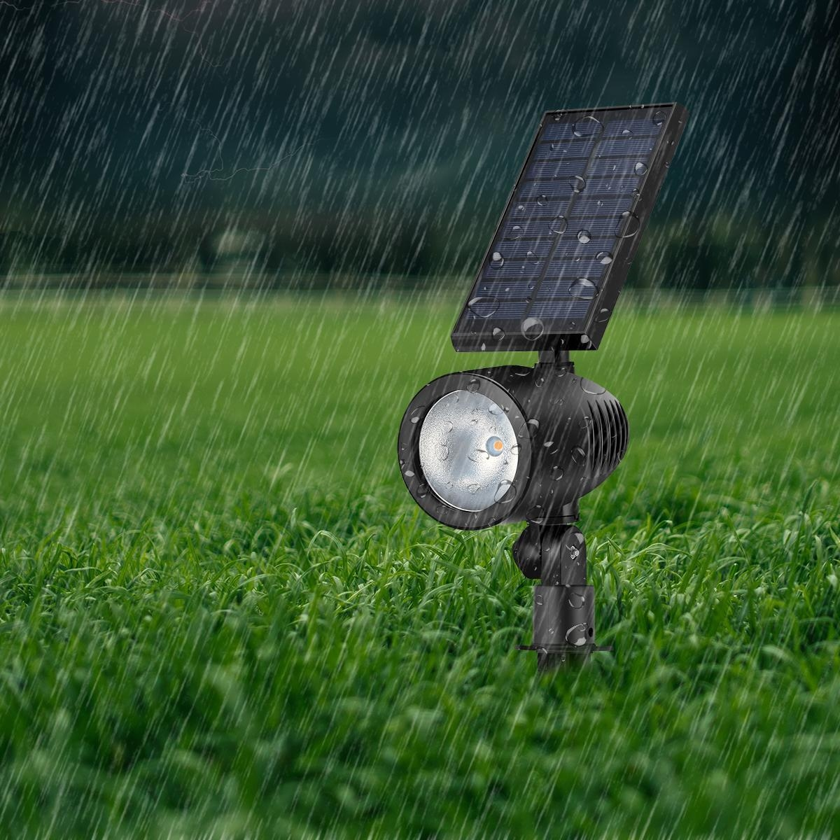 Ein Solarstrahler mit Wasser auf dem Solarpanel, im Regen auf einem grünen Rasen.